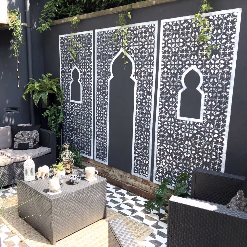 Garden stencil depicting moroccan arches in white on a black wall.