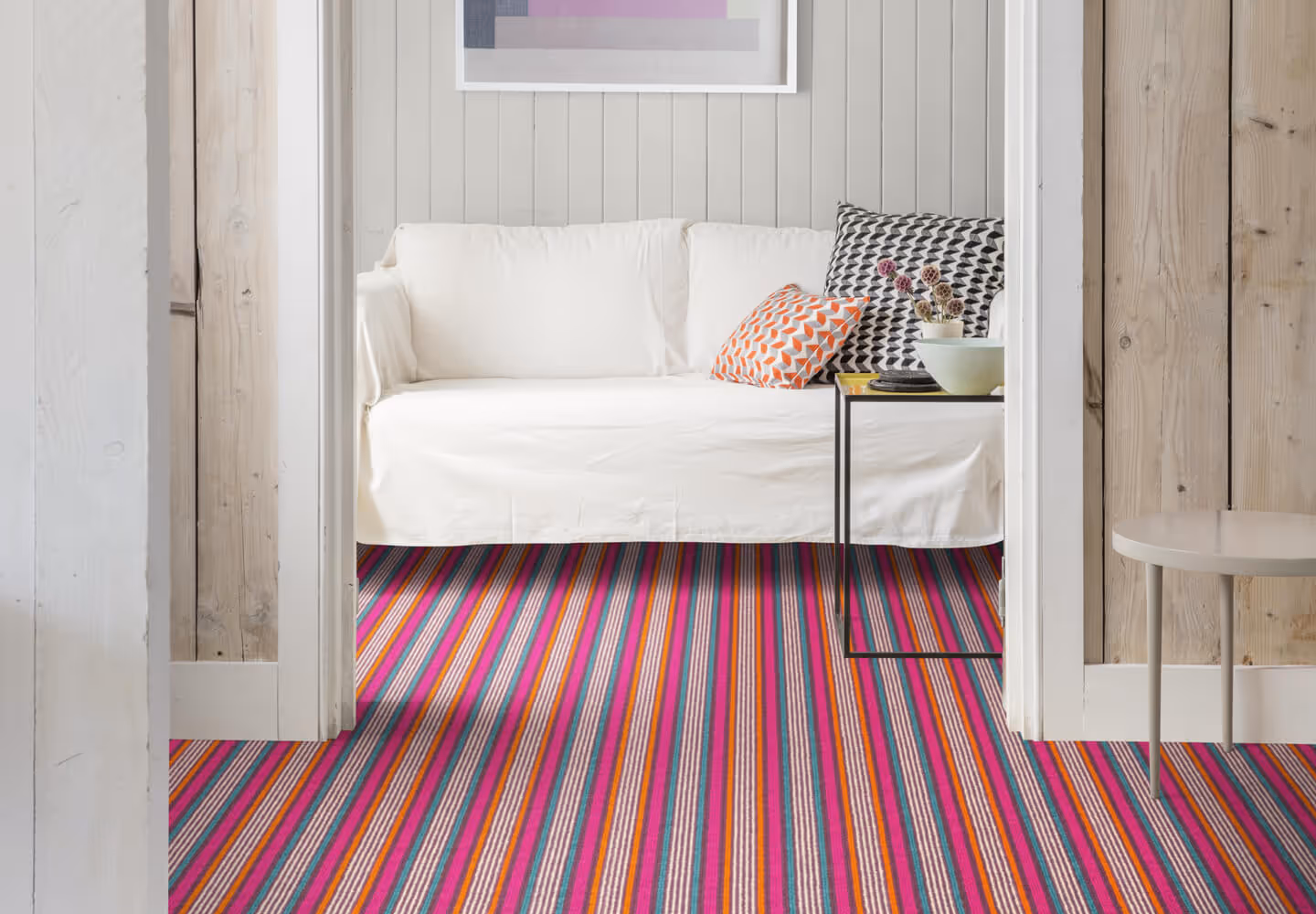 A room with a brightly coloured pink, turquoise and orange striped carpet.