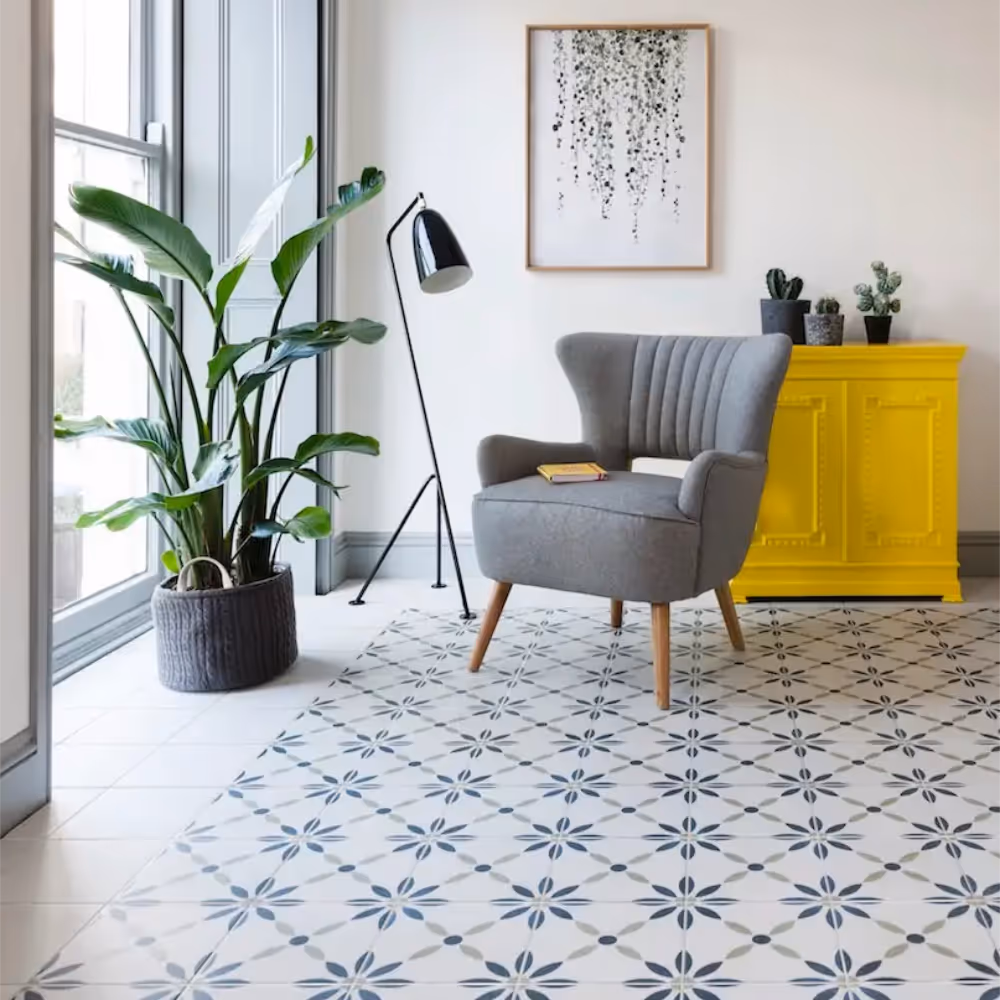 A bright and airy living room with a bright yellow cabinet, grey chair and a patterned tiled floor.