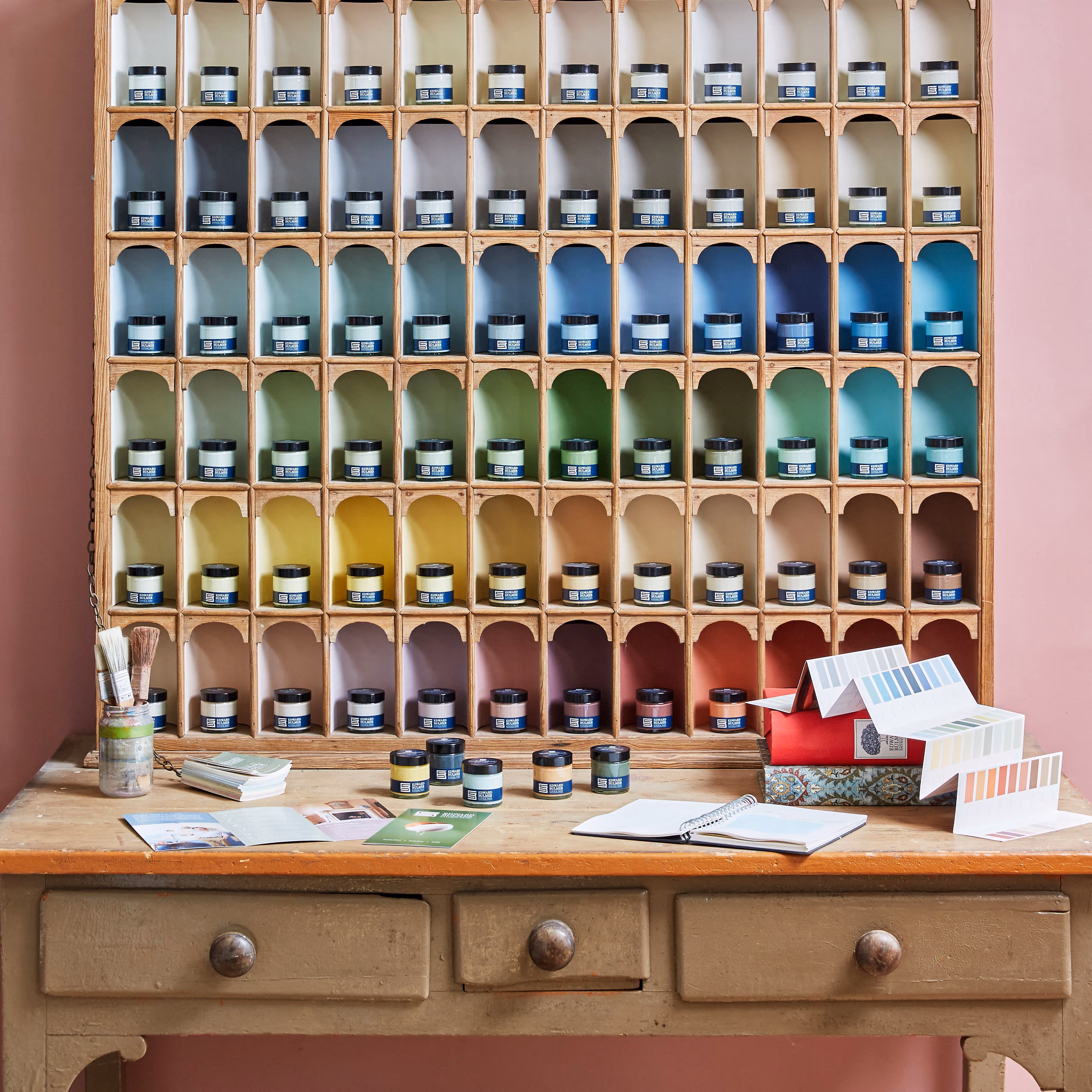 A wooden shelf unit full of paint sample pots.