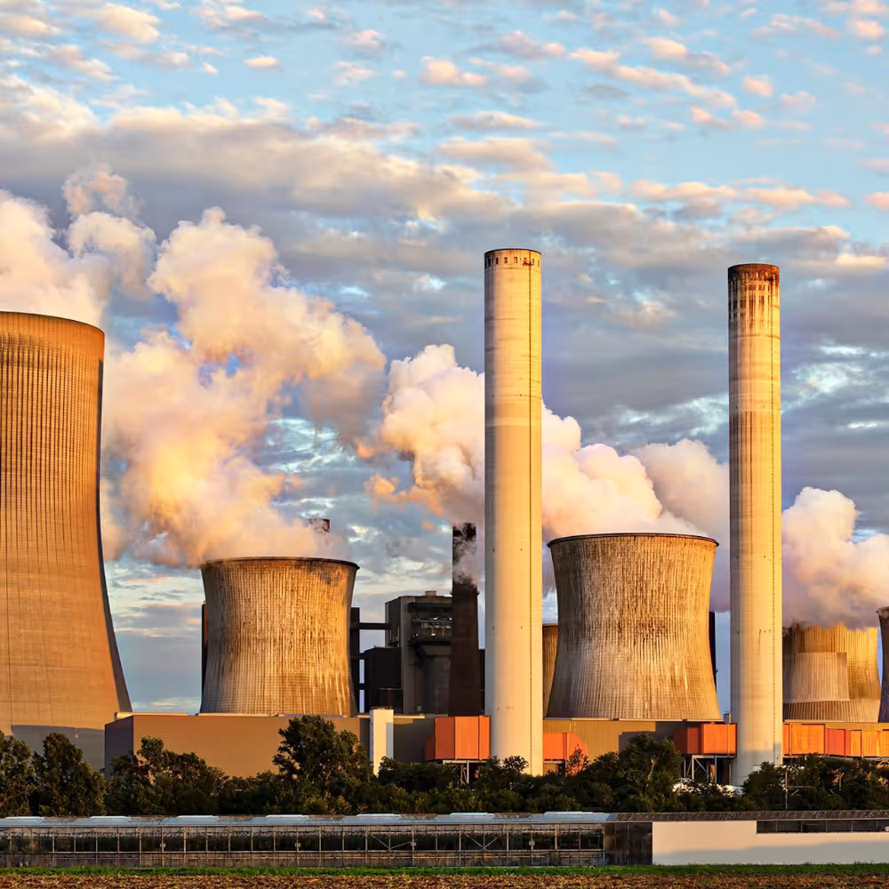 Giant factory chimneys billowing out smoke and pollution from burning fossil fuels.