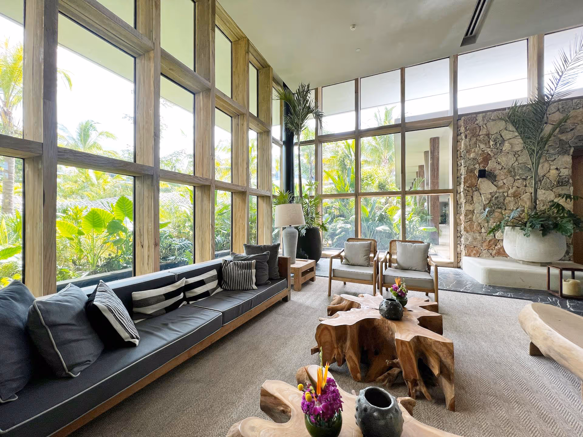 A large room with a huge sofa and expansive windows looking out onto a lush garden.