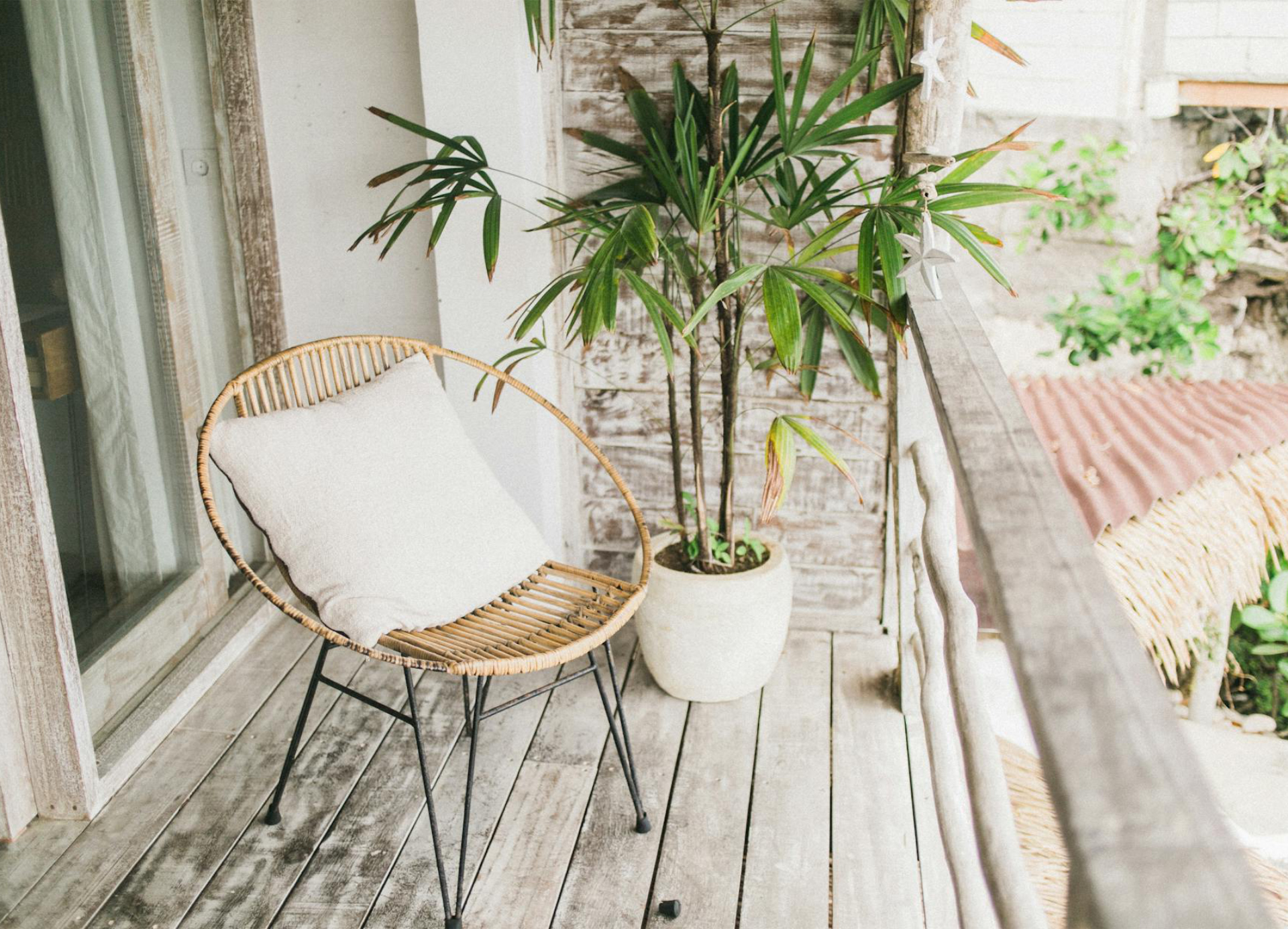 A balcony with a mid century tub chair and potted plant.