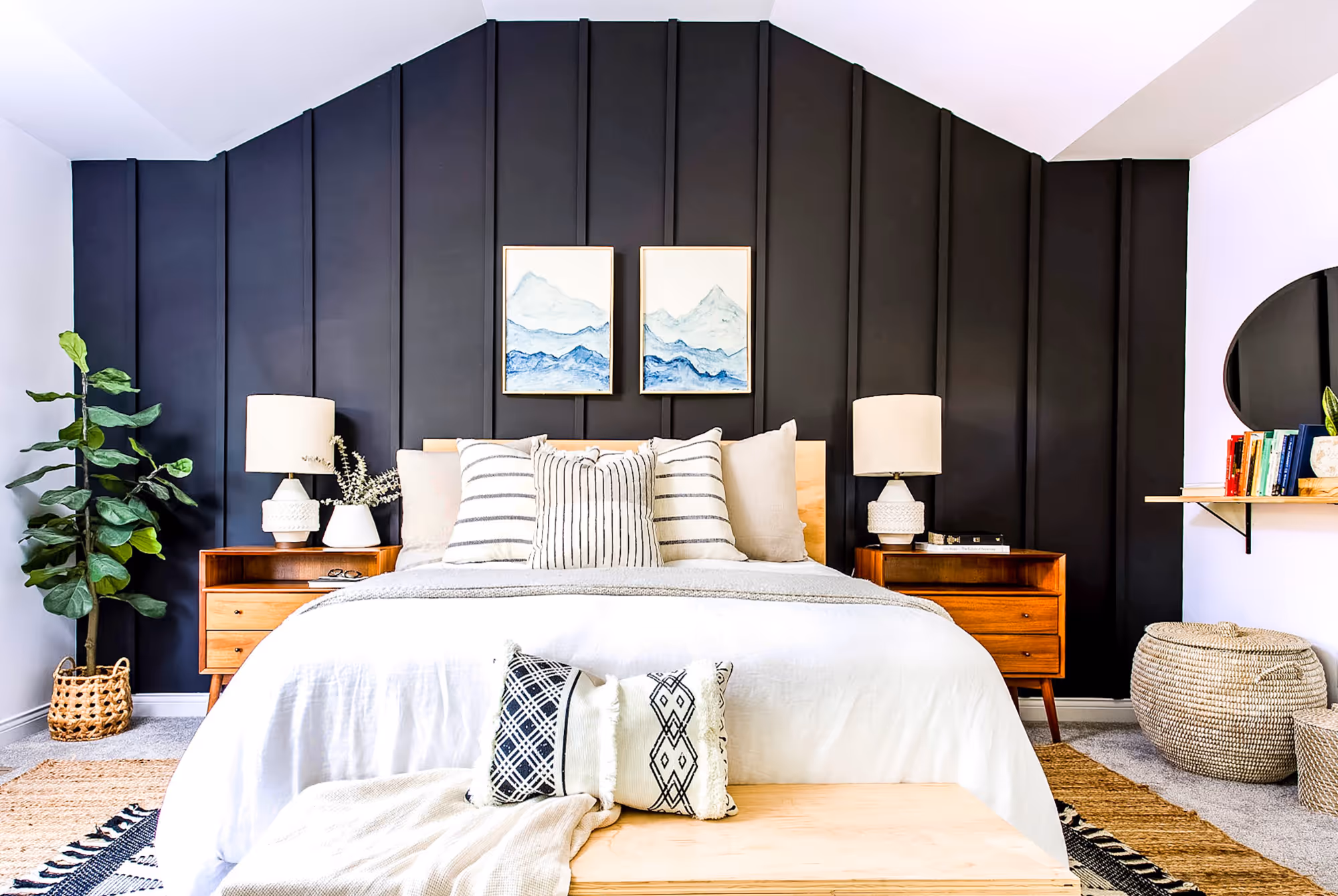 A white bedroom with a black painted panelled wall behind the bed