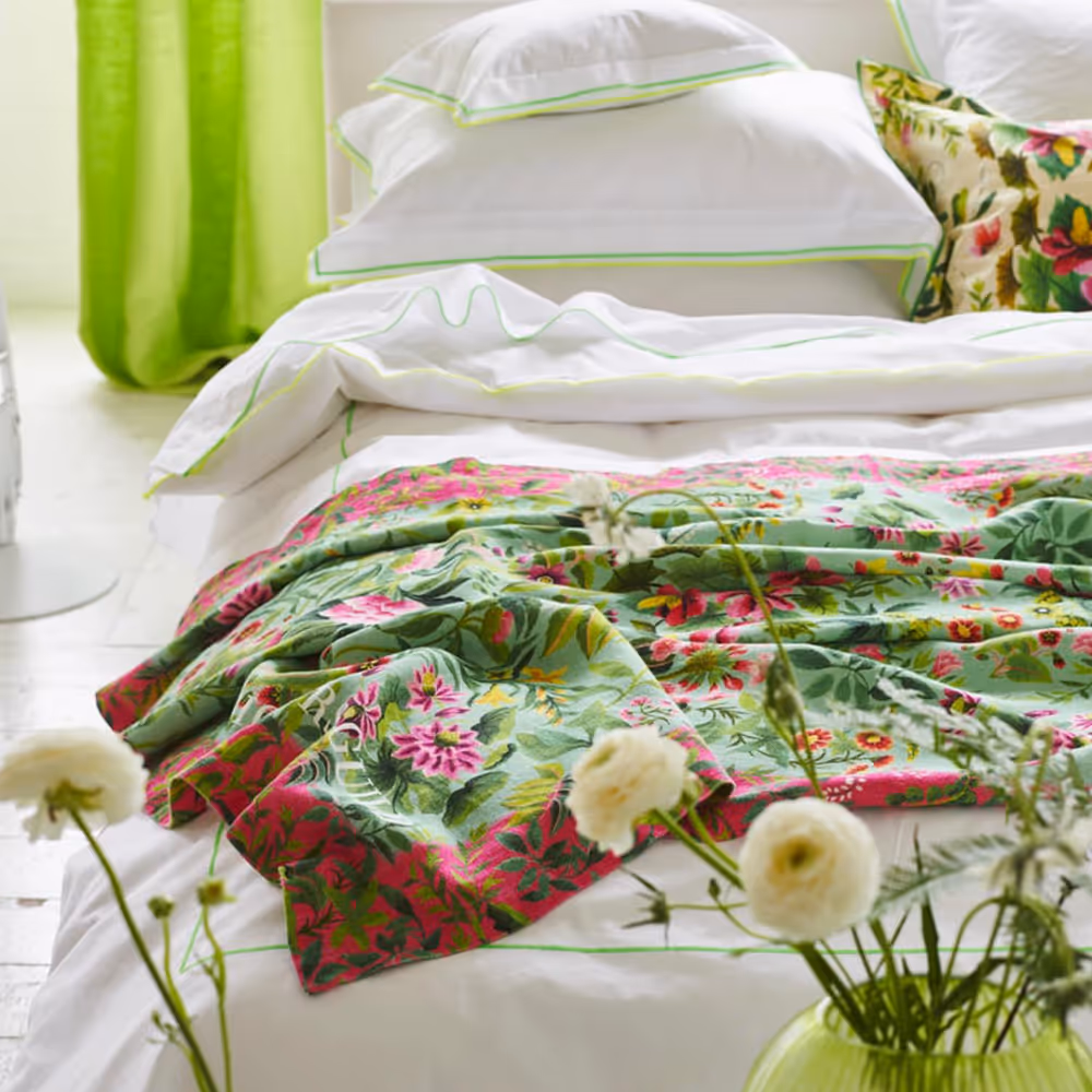A bed with natural linen bedding in a floral design in greens and pinks.