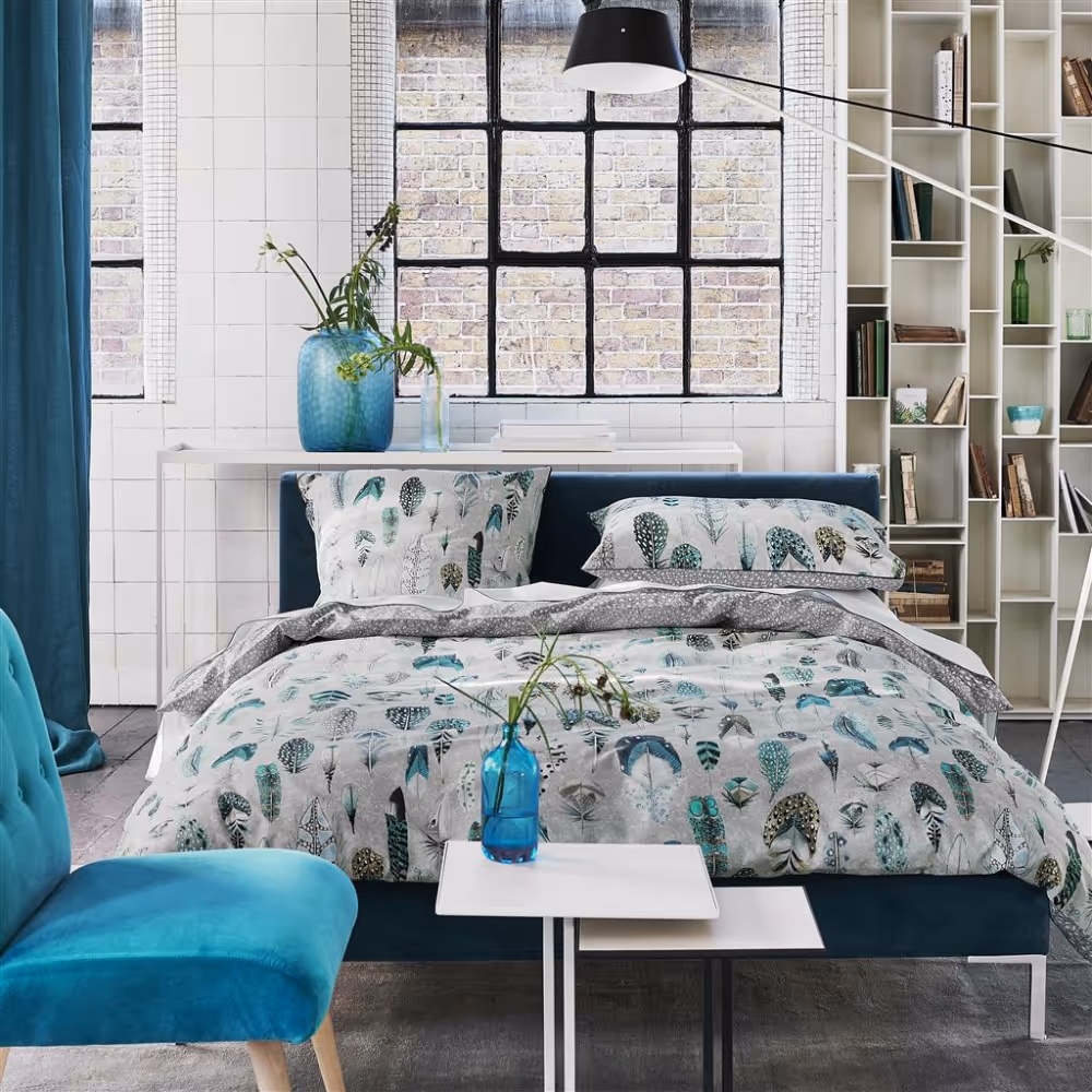 A pared back industrial feel bedroom with white walls and feather themed bed linen.