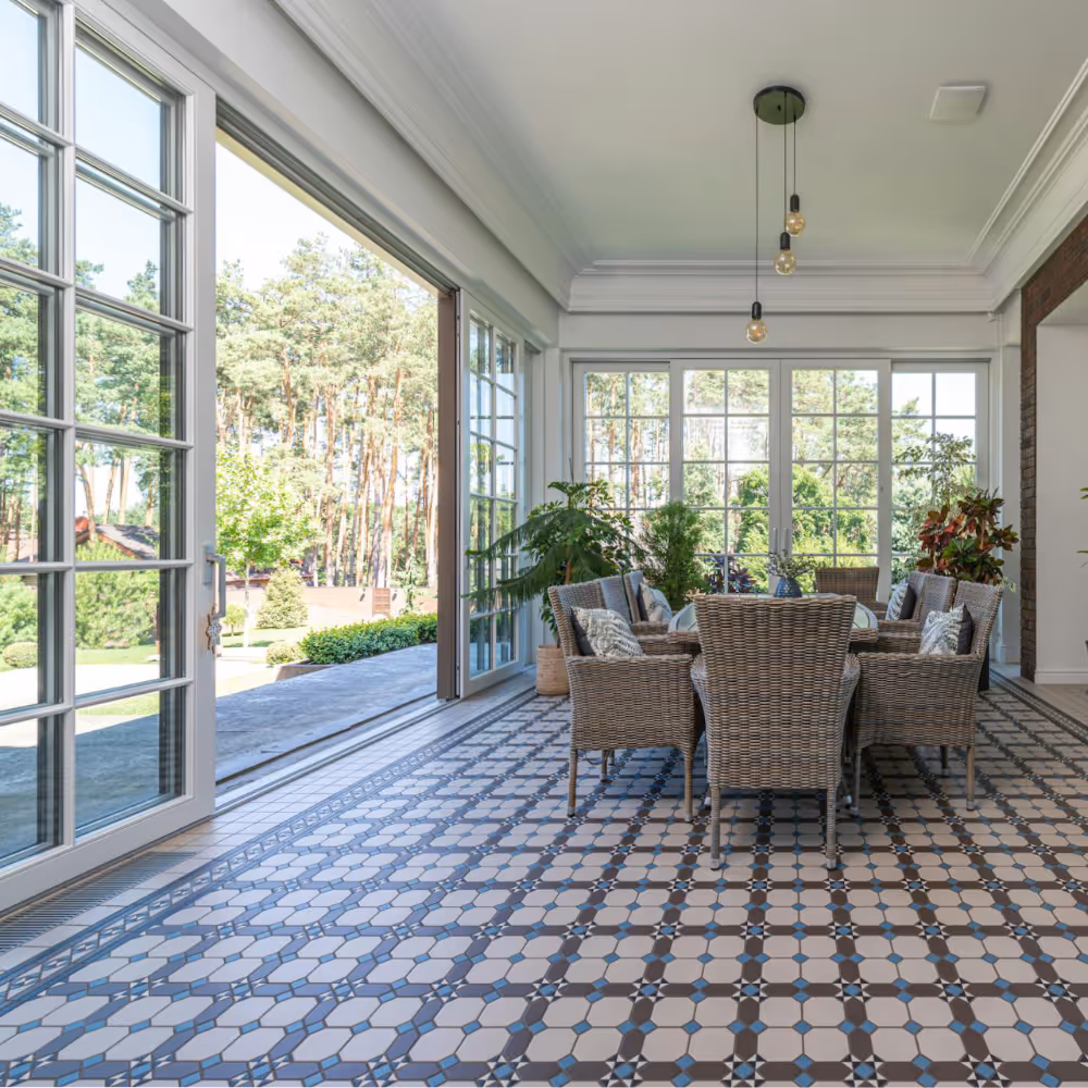 A garden room with rattan dining furniture and a tiled floor.