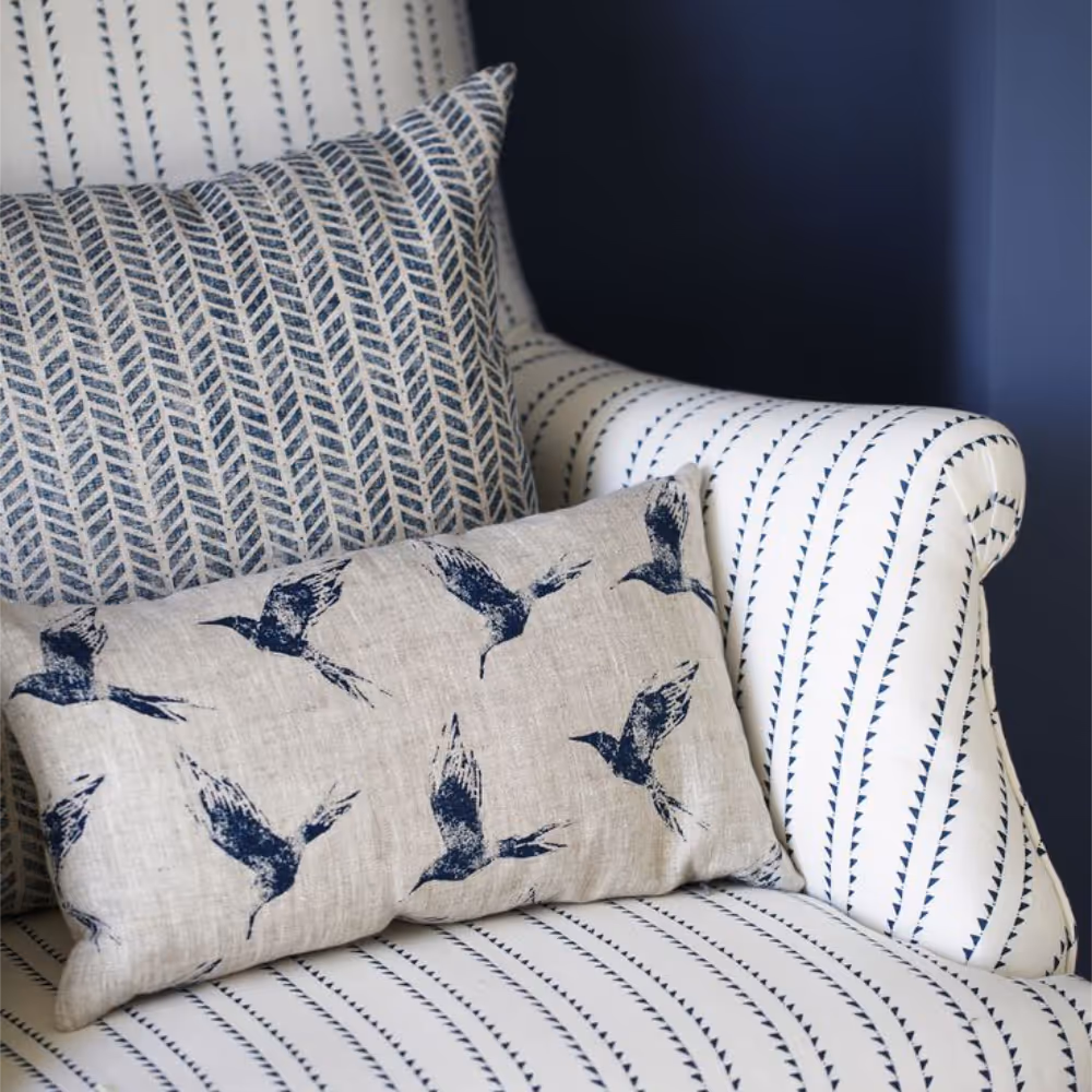 A white and blue stripe armchair with blue and natural linen cushions.